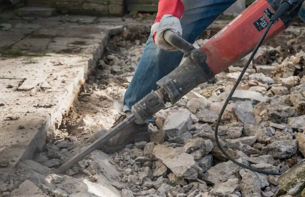 Worker using a power jackhammer for concrete slab breaking and removal in Surrey, BC