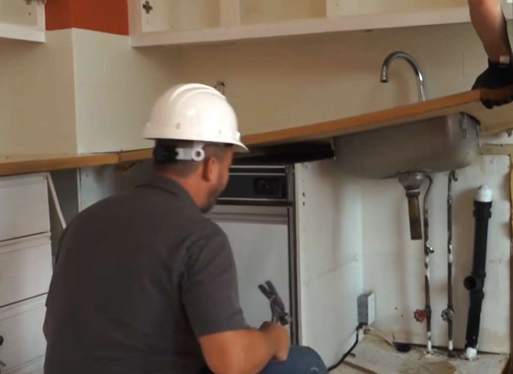 Worker wearing a hard hat removing kitchen countertops during interior demolition in Surrey, BC