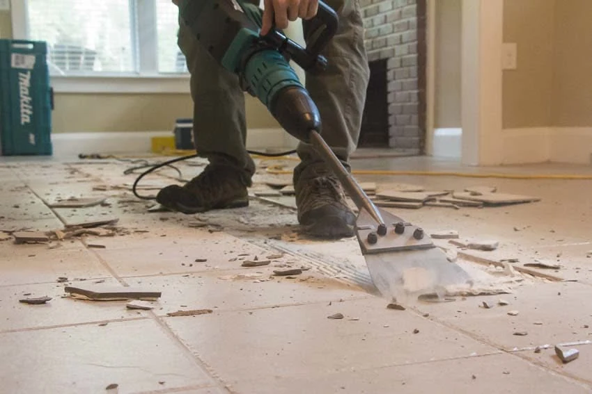 Worker using power scraper tool for tile demolition and floor removal in Surrey, BC.